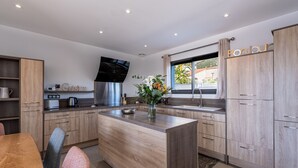 Eine moderne Küche mit Holzschnitzereien, einer zentralen Kochinsel, einem eingebauten Backofen und einem Fenster mit Aussicht.