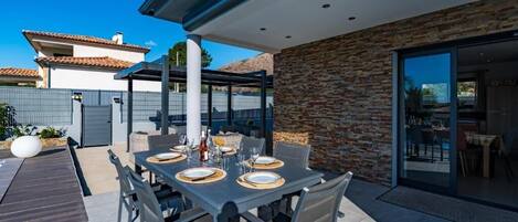 An outdoor patio with a dining table set for four, surrounded by chairs.