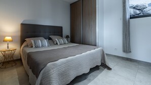Ein modernes Schlafzimmer mit einem großen Bett, einem Nachttisch, einer Lampe und einem Kleiderschrank.