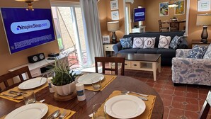 A dining area with a table set for two, a sofa, and a television displaying InspireSleep.com. - HOME AWAY FROM HOME -VACATION VILLA  (Kissimmee)