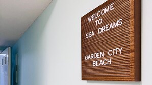A welcome sign with the text "WELCOME TO SEA DREAMS GARDEN CITY BEACH" mounted on a wall. - Walk Across the Street to Beautiful Soft Sandy Beach! (Murrells Inlet)