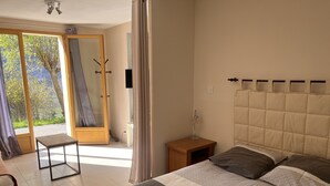 Un dormitorio con cama, mesita de noche, lámpara, una silla y puerta corrediza de vidrio que da a un balcón.