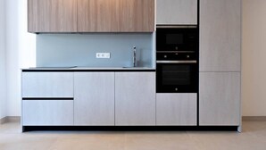 A modern kitchen with grey cabinetry, a built-in oven, and a countertop. - Rooms & Suites Loft 2F en el Centro de Arrecife (Arrecife)