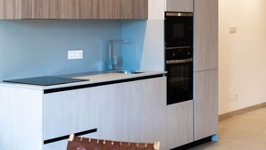 Une cuisine moderne avec des meubles en bois clair, un évier en acier inoxydable et des appareils électroménagers intégrés.