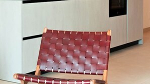 Une cuisine moderne dotée d’un four encastré et d’une chaise rouge à coussin placée devant.
