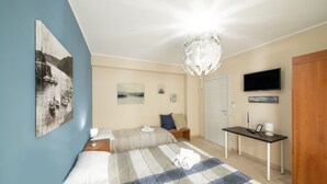 Una habitación de hotel con cama, escritorio, televisor y obras de arte en las paredes.