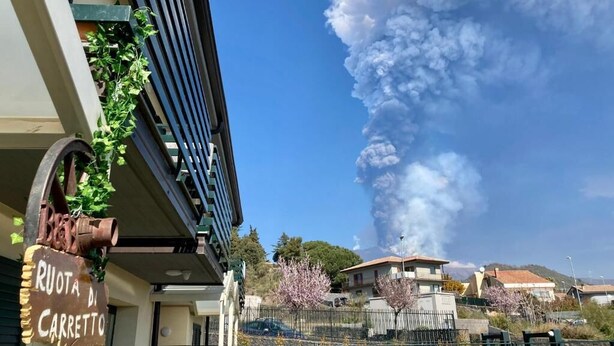 Un edificio con un letrero que dice "RUOTA DI CARRETTO" y una gran columna de humo en el fondo.
