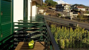 Un balcón con vistas a una montaña, una carretera y edificios residenciales.