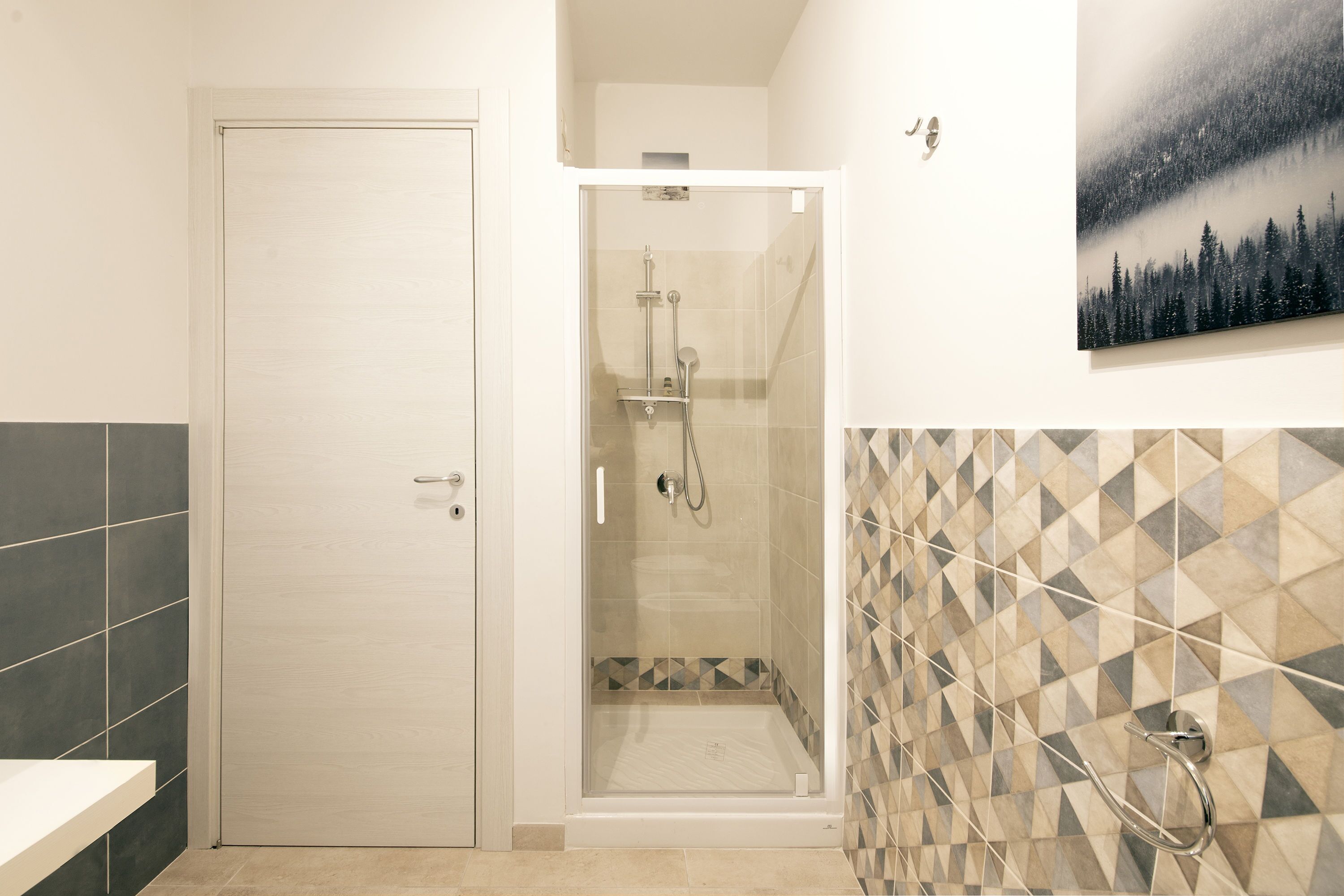 A bathroom with a shower, a door, and a tiled wall.