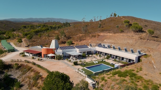 Een modern resort met zonnepanelen, een zwembad en een woestijnlandschap.