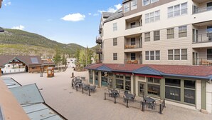 A multi-story hotel with outdoor seating, a mountain backdrop, and a ski lift in the distance. - Buffalo Lodge #8329 by Summit County Mountain Retreats (Keystone)