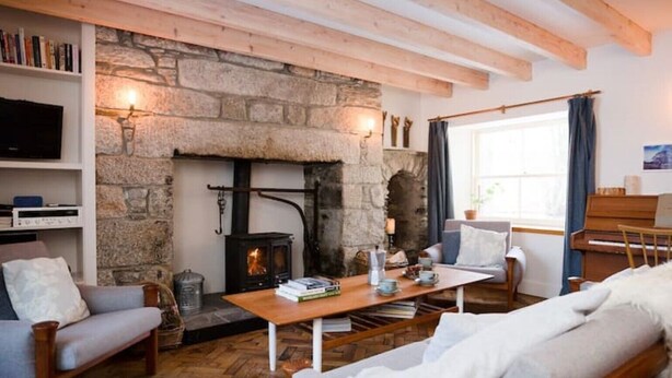 A cozy living room with a stone fireplace, wooden beams, a piano, and comfortable seating. - South Dell - Scandi-style family cottage set on the edge of the Abernethy Forest (Nethy Bridge,)