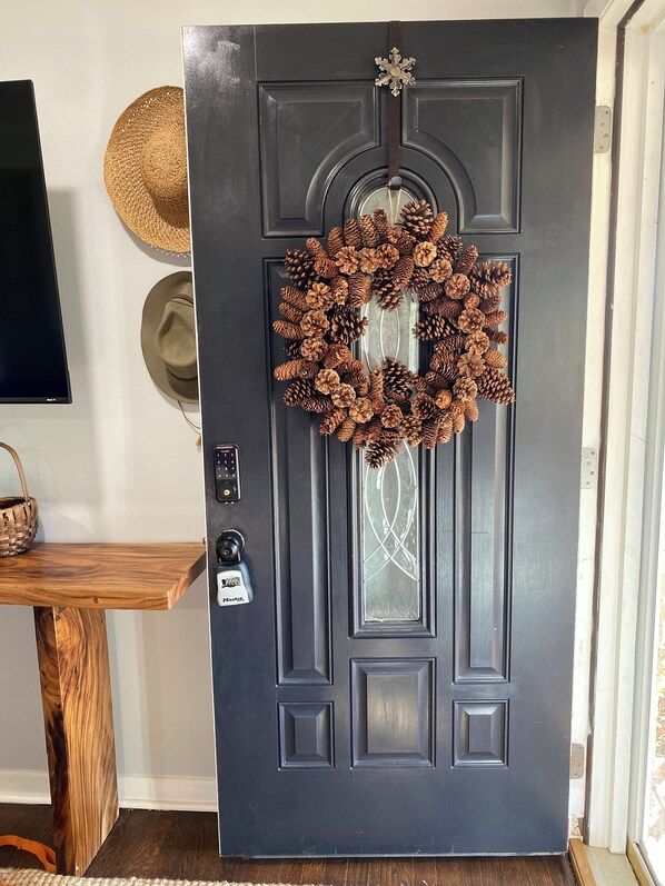 A dark gray door with a pine cone wreath, a star ornament, and a glass panel.