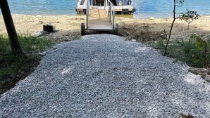 A gravel path leading to a wooden dock with a bench and a small table, overlooking a body of water. - Old Southern - Lakefront - Dog friendly (New Tazewell)