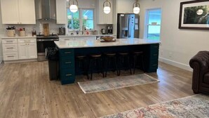A modern kitchen with a large island, white cabinets, and a teal accent wall. - Old Southern - Lakefront - Dog friendly (New Tazewell)