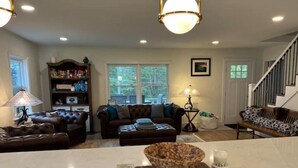 A spacious living room with a marble island, leather sofas, a bookshelf, and a staircase. - Old Southern - Lakefront - Dog friendly (New Tazewell)