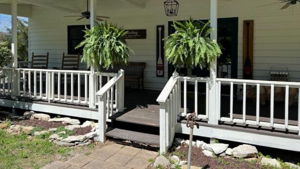 A white porch with a railing, two potted plants, a bench, and a door. - Old Southern - Lakefront - Dog friendly (New Tazewell)