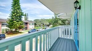 A balcony with a view of a residential street, a tall evergreen tree, and a building with a blue door. - New Smyrna Beach Vacation Rental < 1/2 Mi to Beach (New Smyrna Beach)