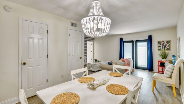 A dining area with a white table, woven placemats, and a chandelier. - New Smyrna Beach Vacation Rental < 1/2 Mi to Beach (New Smyrna Beach)
