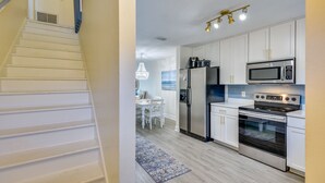 A modern kitchen with white cabinets, stainless steel appliances, and a dining area with a chandelier. - New Smyrna Beach Vacation Rental < 1/2 Mi to Beach (New Smyrna Beach)