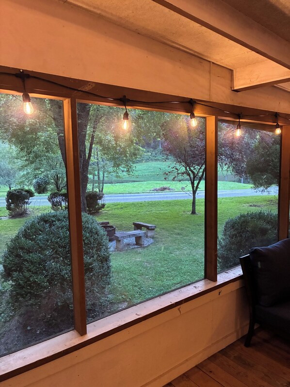 Ein Zimmer mit großem Fenster und Blick auf eine grüne Parklandschaft mit Bäumen und einer Bank.