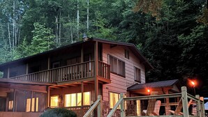 A cabin with a deck, a fire pit, and a staircase leading to the upper level. - Mountain Lake House - Hot tub, fire pit, fish and swim! (Almond)