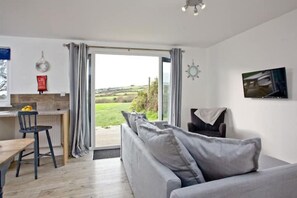Relax in this serene living space with a sofa, flat-screen TV, and dining area.