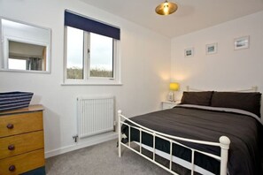 Cozy retreat with a single bed, dresser, and window with a valance.
