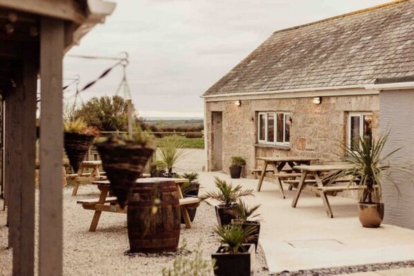 Enjoy a serene outdoor space with a stone building, picnic tables, and potted plants.