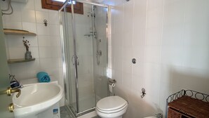 Une salle de bain avec une douche à parois de verre, un lavabo sur colonne, des toilettes et un bidet.