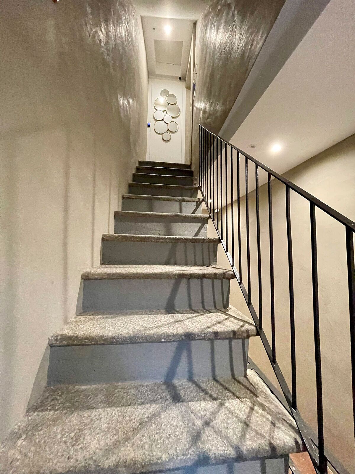 A staircase with a handrail and a wall-mounted light fixture.