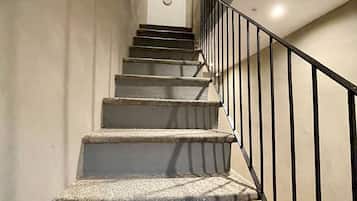 A staircase with a handrail and a wall-mounted light fixture.