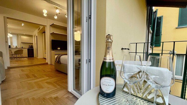 A room with a bed, a table with a bottle of champagne, and a glass on the table. - Bellagio Luxury Suites Apartments (Bellagio)
