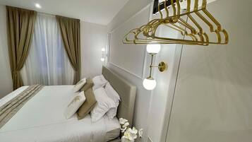 A modern hotel room with a neatly made bed, a wall-mounted light fixture, and a clothing rack.