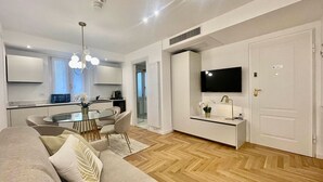 A modern living room with a sofa, a glass coffee table, and a TV mounted on the wall. - Bellagio Luxury Suites Apartments (Bellagio)