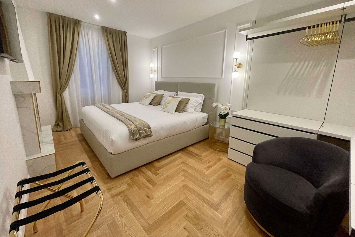 A modern bedroom with a bed, bedside table, dresser, chair, and a mirror.