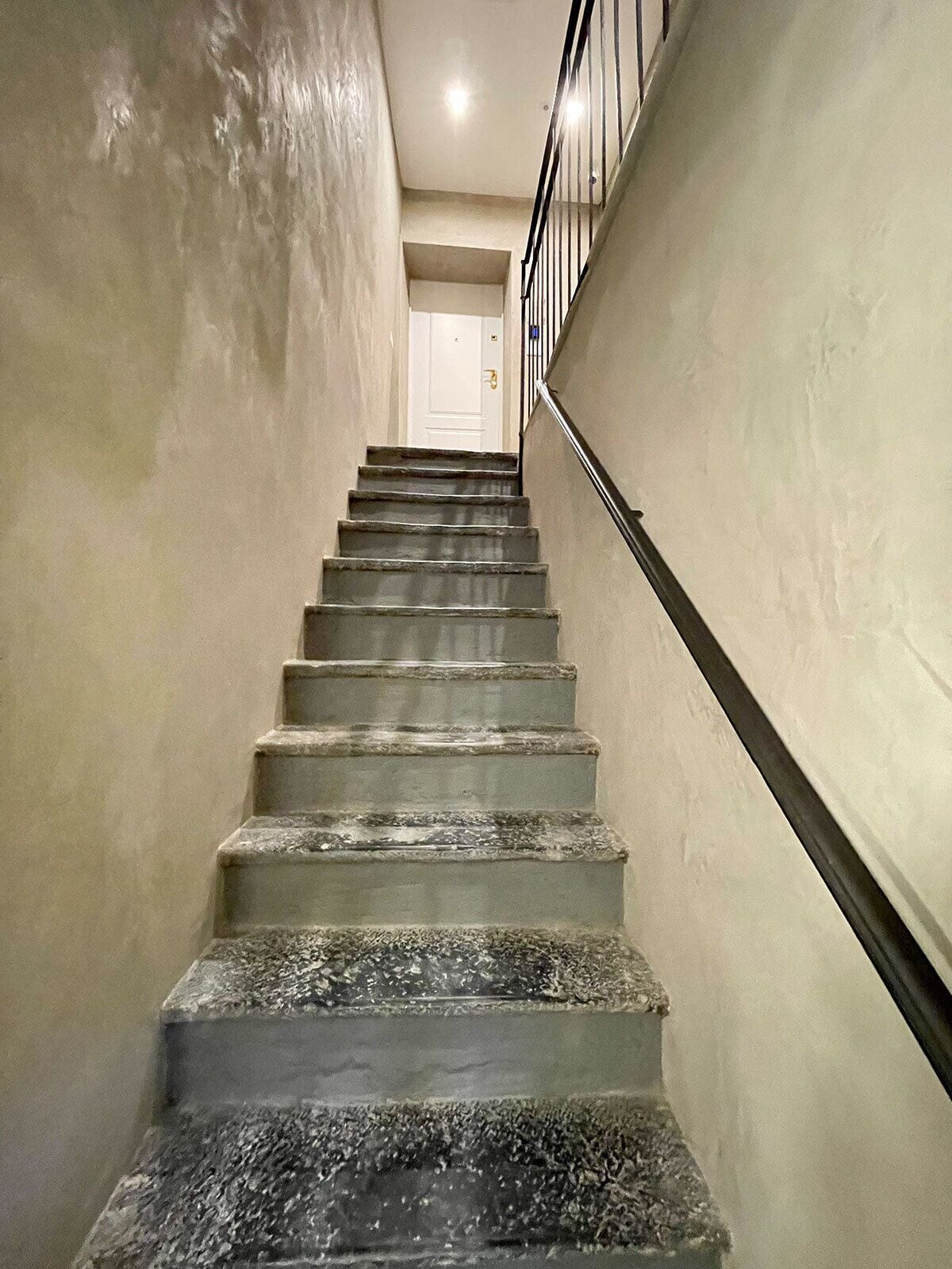 Eine Treppe mit Handlauf, die zu einer Tür oben führt.