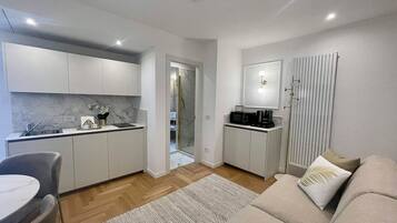 A modern kitchen with white cabinets, a marble backsplash, and a built-in microwave.