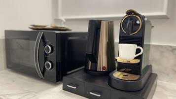 A modern kitchen with a coffee machine, a microwave, and a coffee maker.