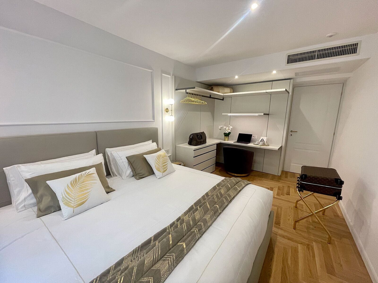 Een moderne slaapkamer met een bed, nachtkastjes, een bureau, een stoel en een kledingkast.