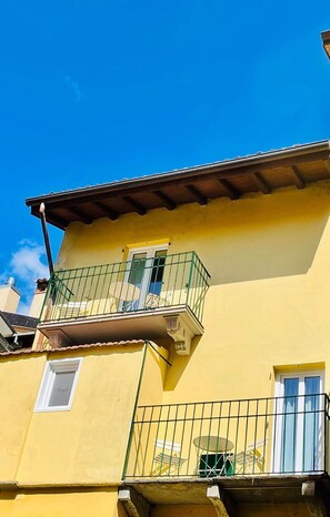 A yellow building with a balcony, a window, and a door. - Bellagio Luxury Suites Apartments (Bellagio)