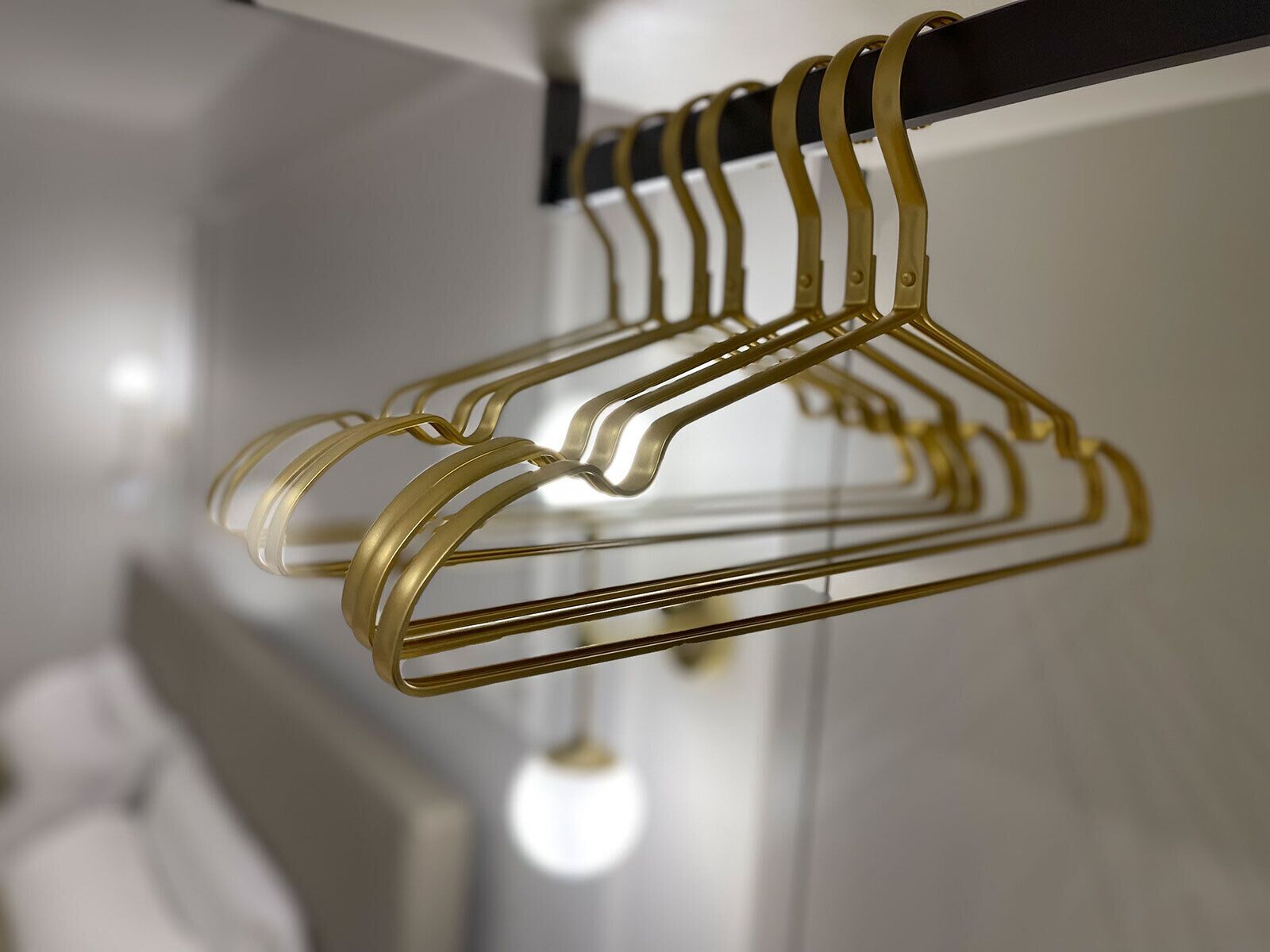 Gouden metalen kledinghangers aan een zwarte stang.