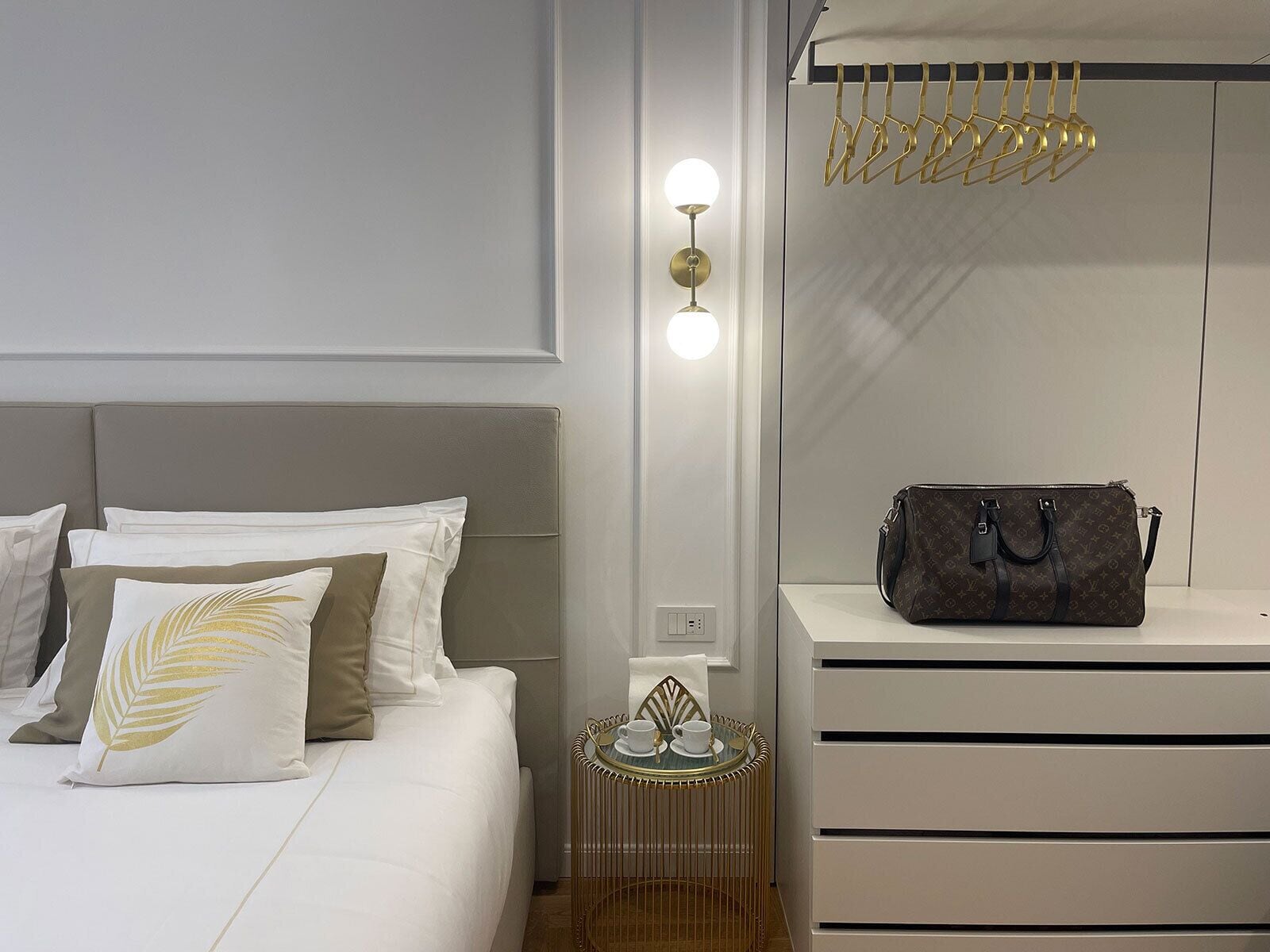A modern bedroom with a bed, bedside table, lamp, and a hanging coat rack.