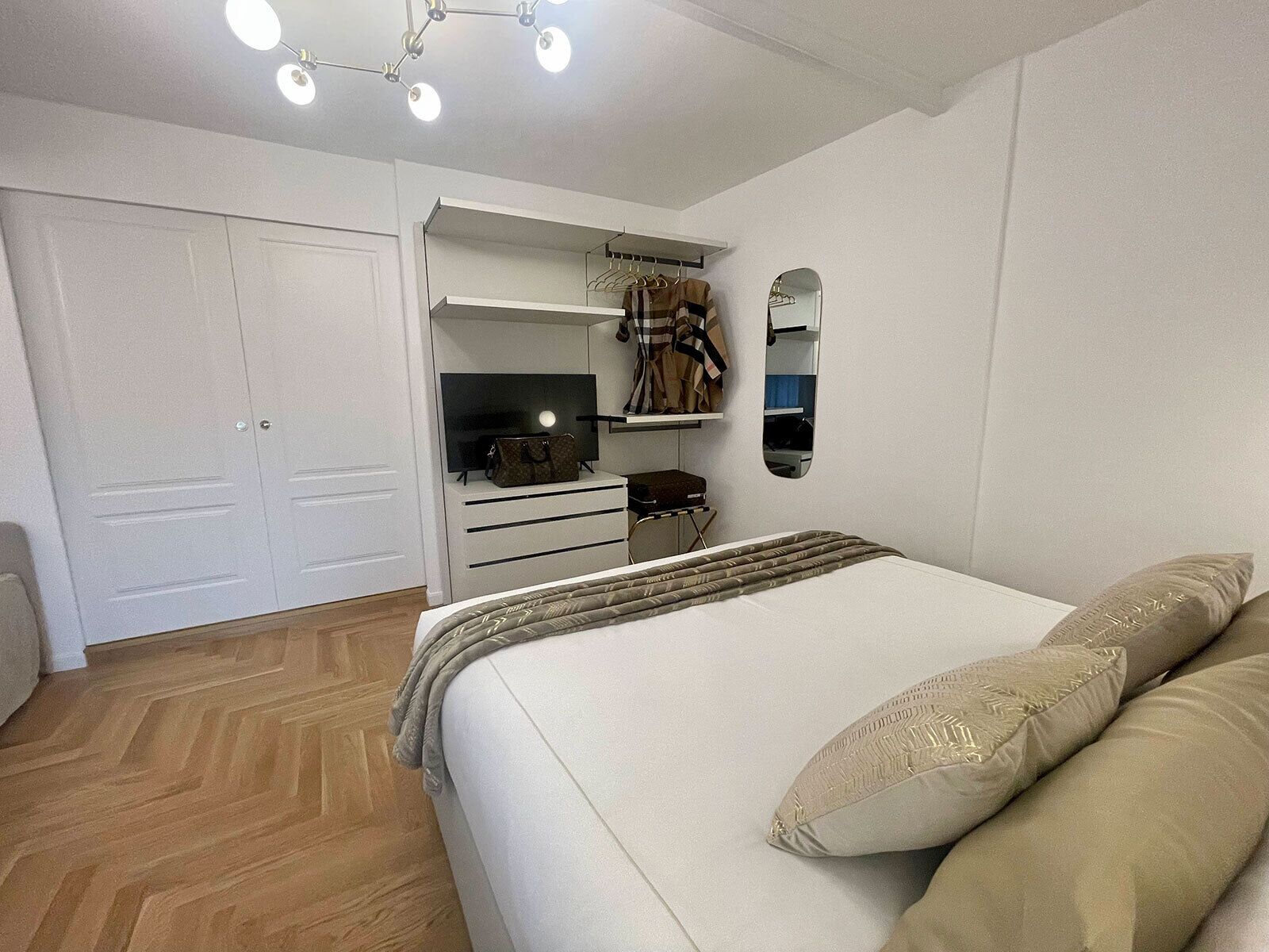 Un dormitorio con cama, armario, espejo y televisión.