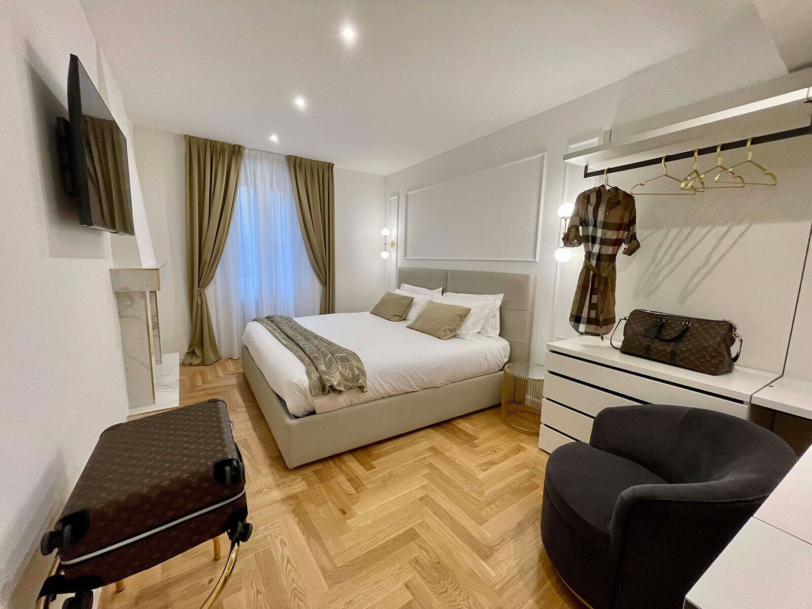 Ein Hotelzimmer mit Bett, Schreibtisch, Stuhl, Kleiderschrank und Fernseher.