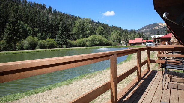 Un pontile in legno con vista su un fiume, sullo sfondo una montagna ricoperta da una fitta vegetazione.