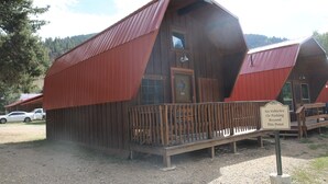 Une cabane en bois avec un toit rouge, une terrasse en bois et un panneau indiquant qu’il est interdit de poursuivre en véhicule au-delà de ce point.