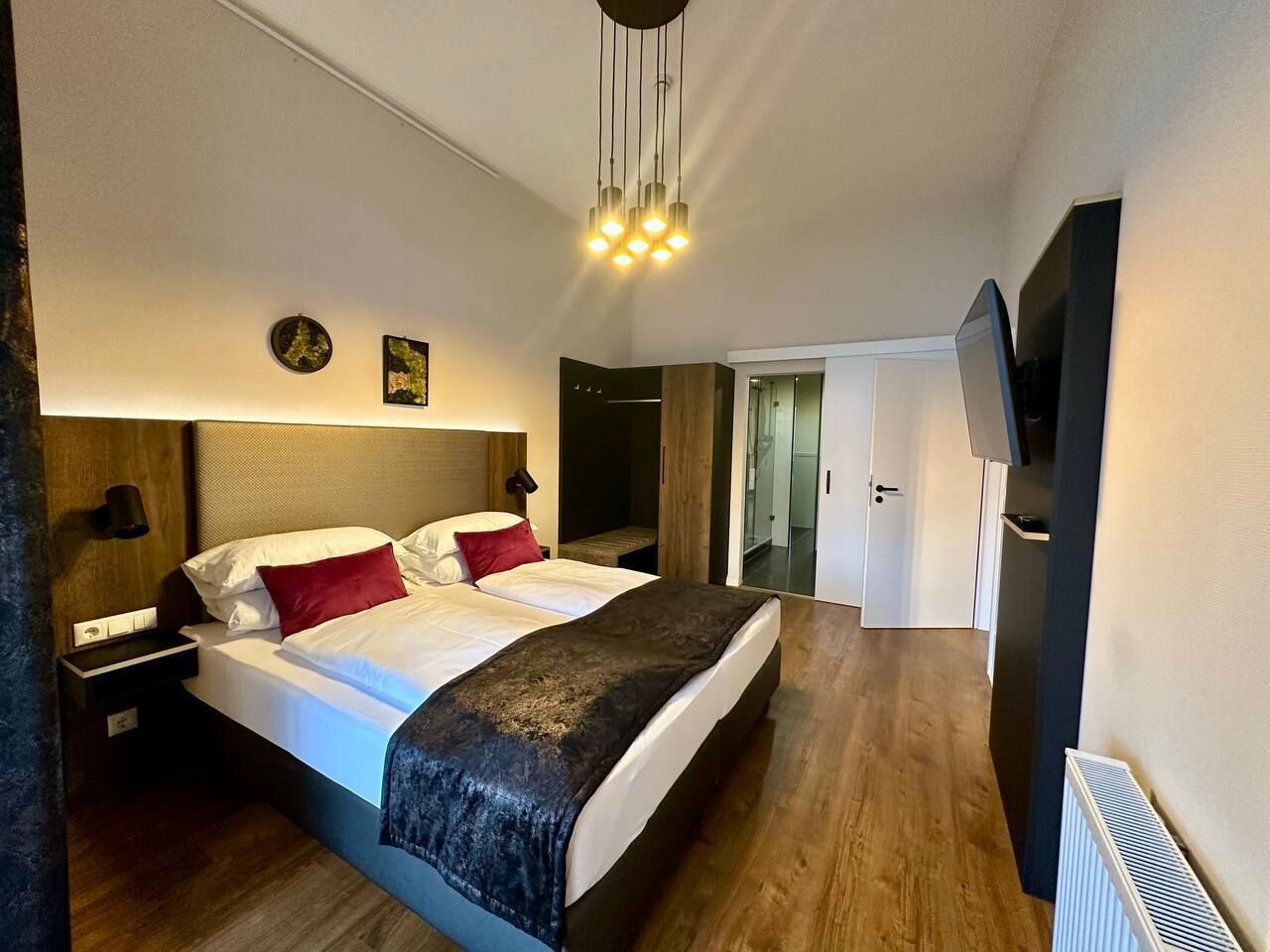 Ett modernt hotellrum med en stor säng, sängbord, en platt-TV och en taklampa.
