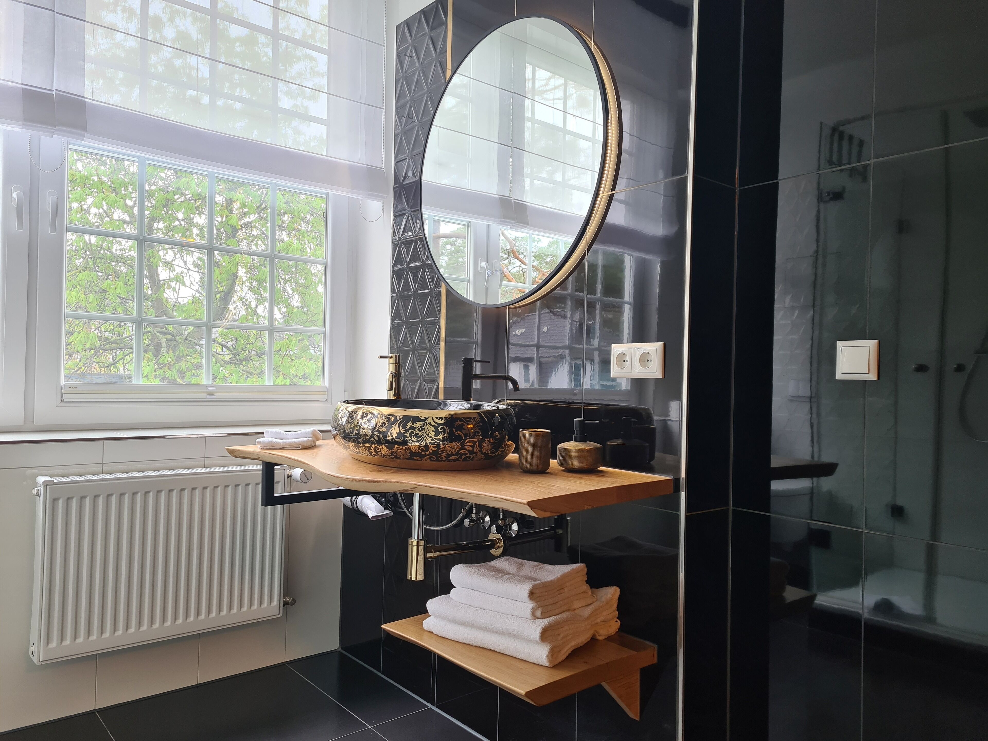 Une salle de bain moderne avec un grand miroir ovale, un lavabo sur colonne et un porte-serviettes.