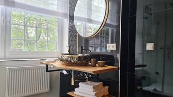 Une salle de bain moderne avec un grand miroir ovale, un lavabo sur colonne et un porte-serviettes.